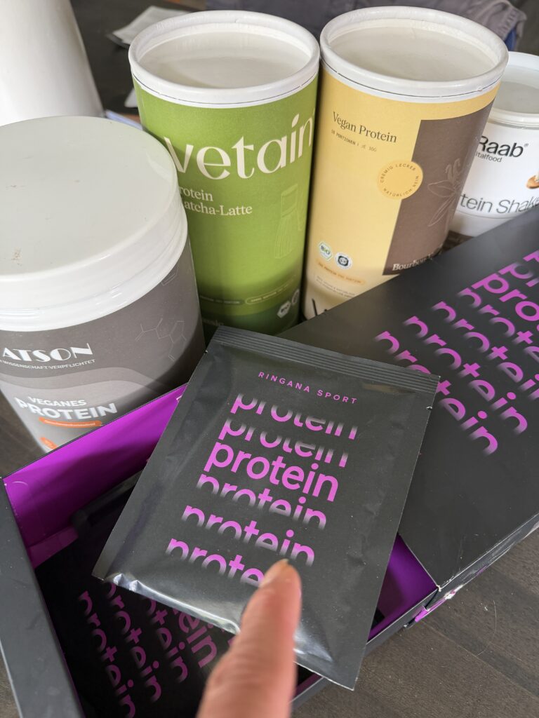 Vier vegane Proteinpulver im Vergleich: Watson, Vetain, Raab Pur und RINGANA Sport auf einem Tisch